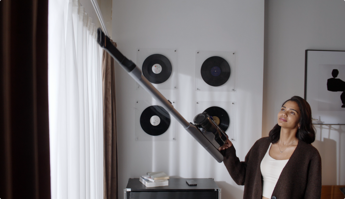 Woman cleaning high curtains with the Narwal V50 Cube extension wand