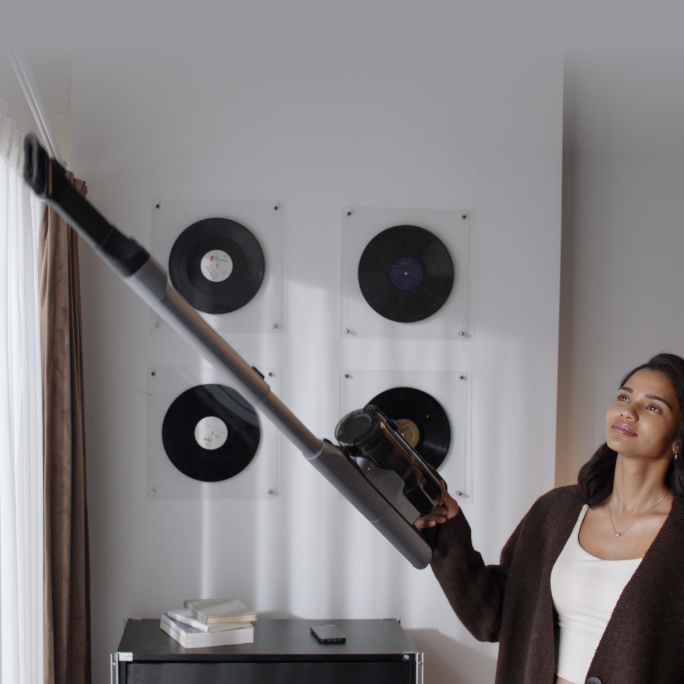 Woman cleaning high curtains with the Narwal V50 Cube extension wand
