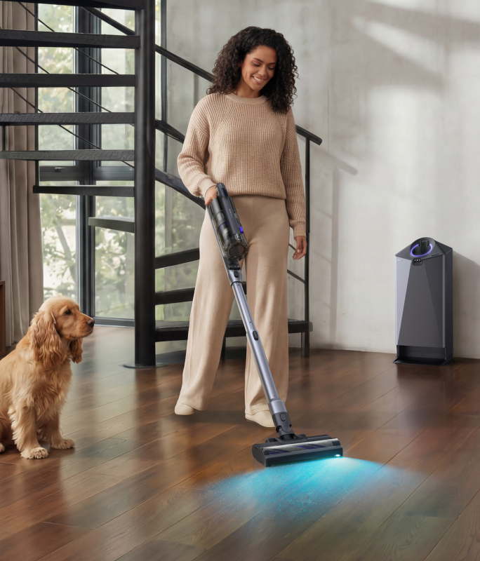 Woman vacuuming with the Narwal V50 Cube near a staircase and dog